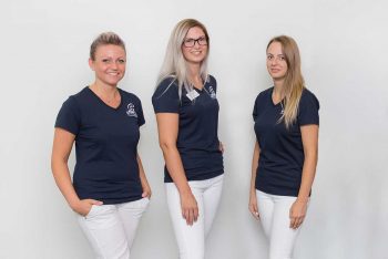 Vier Personen in marineblauen Oberteilen und weißen Hosen von SH Wittlich stehen vor einem schlichten weißen Hintergrund.